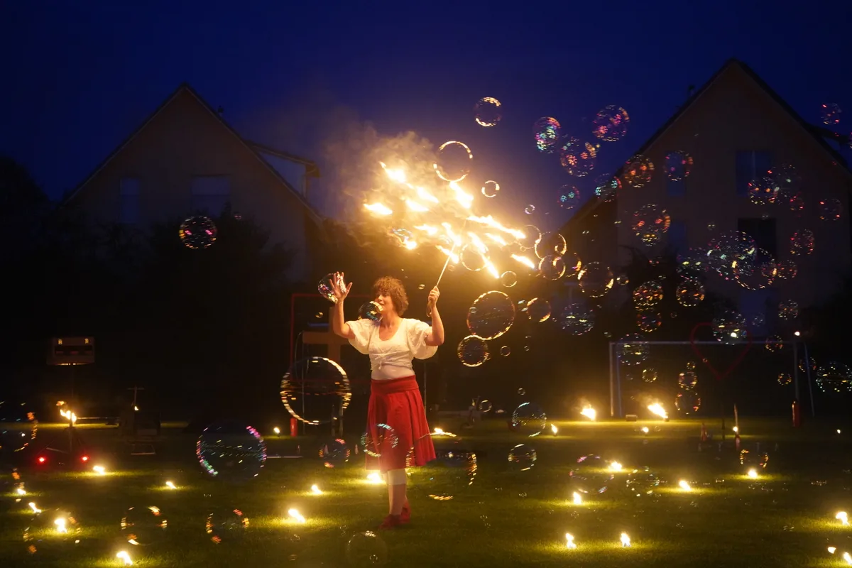 Eine Frau mit brennendem Schirm und mit Seifenblasen.